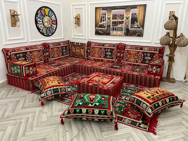 L-shaped Arabic Majlis sofa set with red ethnic cushions and floor pillows, perfect for a cozy living room.